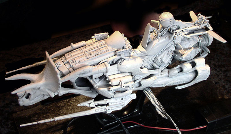 Maquette de motovolante en montage, vue latérale détaillée avec pilote, hélice et structure mécanique apprêtée en gris