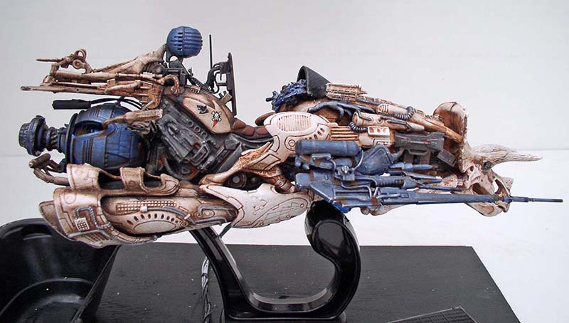 Maquette de motovolante science-fiction détaillée beige et bleue sur socle noir transparent