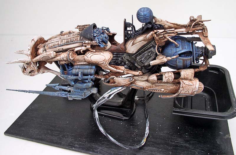 Maquette de motovolante futuriste aux détails beige et bleu sur socle noir