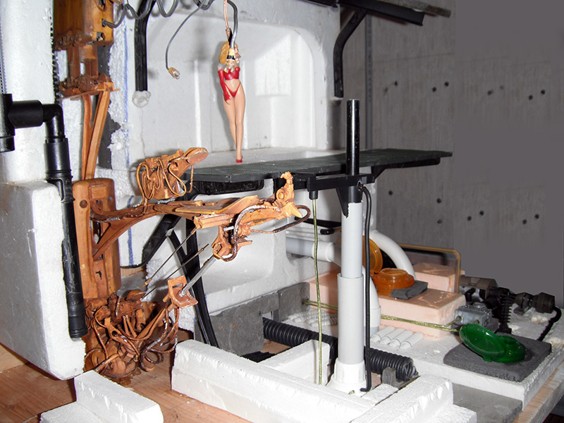 Maquette de motovolante en construction avec structure en bois et figurine féminine suspendue