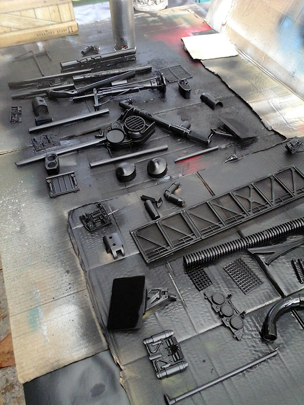 Pièces de maquette du motovolante peintes en gris foncé séchant sur un carton