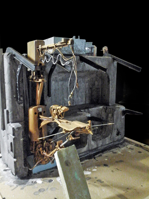 Maquette de motovolante en laiton doré dans un décor sombre d'atelier industriel patiné