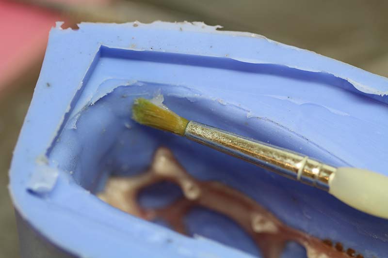 Application au pinceau d'un agent démoulant dans le moule en silicone bleu du crâne