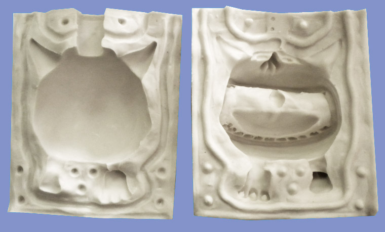 Deux parties d'un moule souple en silicone blanc montrant l'empreinte creuse d'un personnage