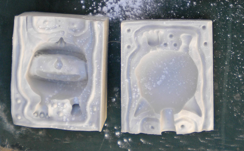 Deux parties d'un moule souple en silicone blanc ouvert montrant l'empreinte d'une figurine