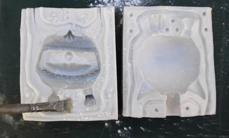 Deux parties d'un moule en silicone blanc poudrées de talc avec un pinceau