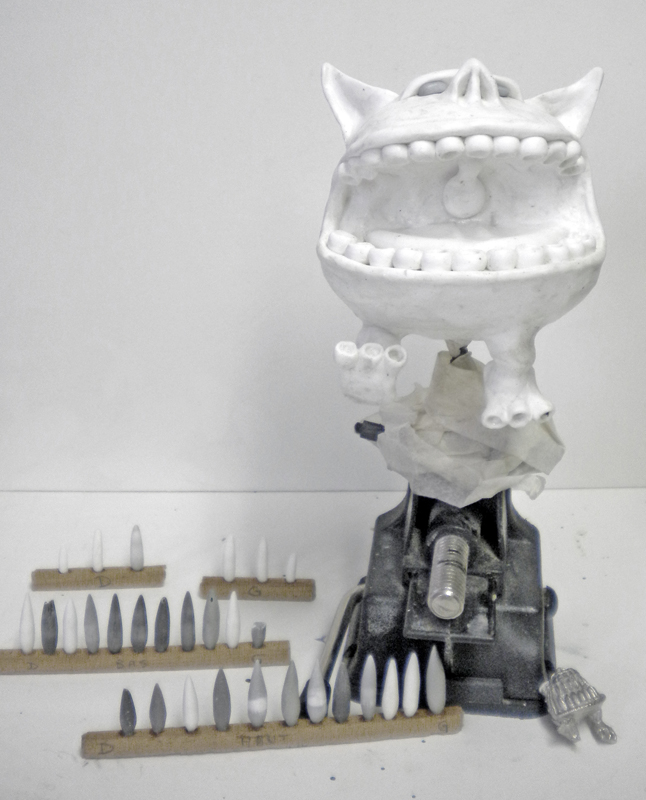 Maquette de créature blanche à grande gueule dentée avec dents en résine alignées sur supets