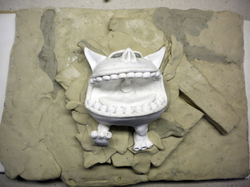 Figurine de créature à grandes dents partiellement enchâssée dans un lit de pâte à modeler