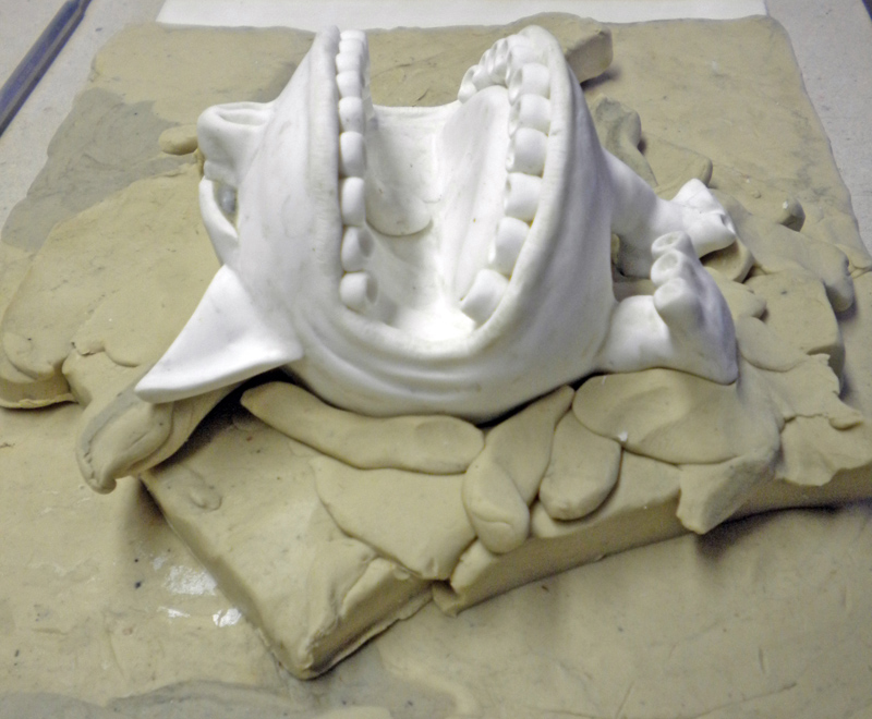 Pièce blanche en plâtre enchâssée dans un lit de pâte à modeler avant moulage silicone