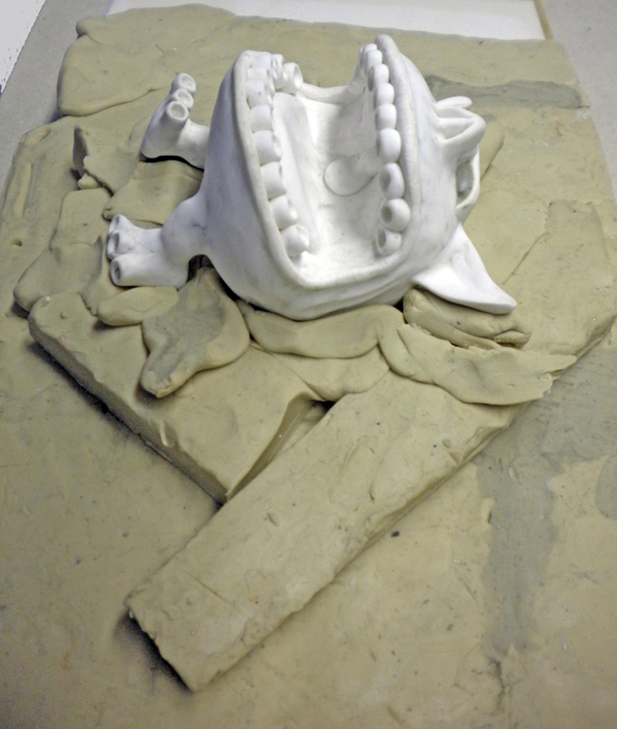 Modèle de figurine blanc enrobé dans la pâte à modeler pour préparer le moule