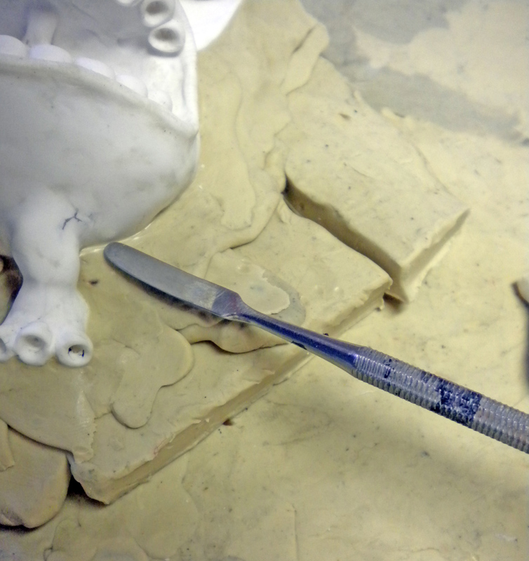 Modelage du lit de pâte à modeler autour de la pièce avec une spatule