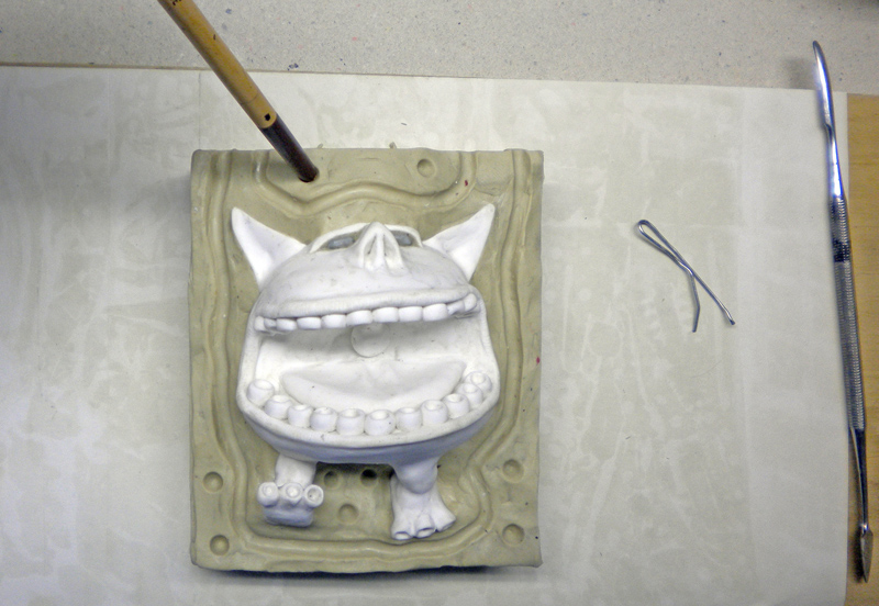 Tirage en plâtre d'une créature souriante démoulé du moule souple en silicone