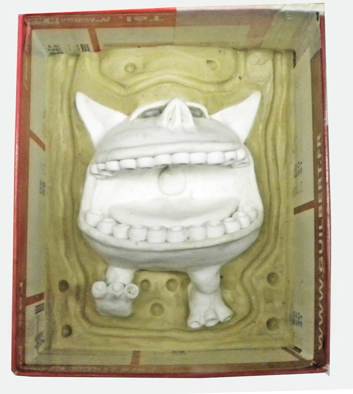 Figurine blanche d'un monstre souriant démoulée sur son moule en silicone