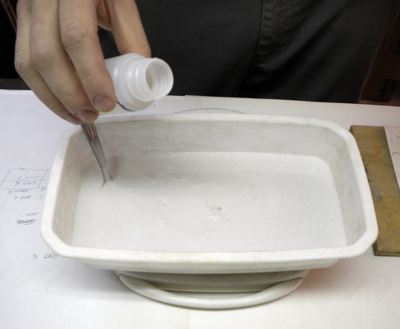 Versement du catalyseur durcisseur dans l'élastomère de silicone liquide blanc d'un récipient