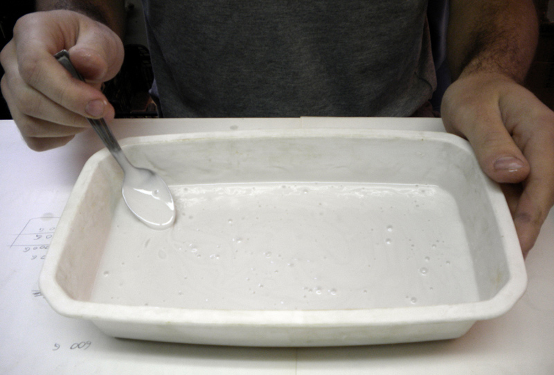 Mélange à la cuillère de l'élastomère de silicone liquide dans un bac en plâtre