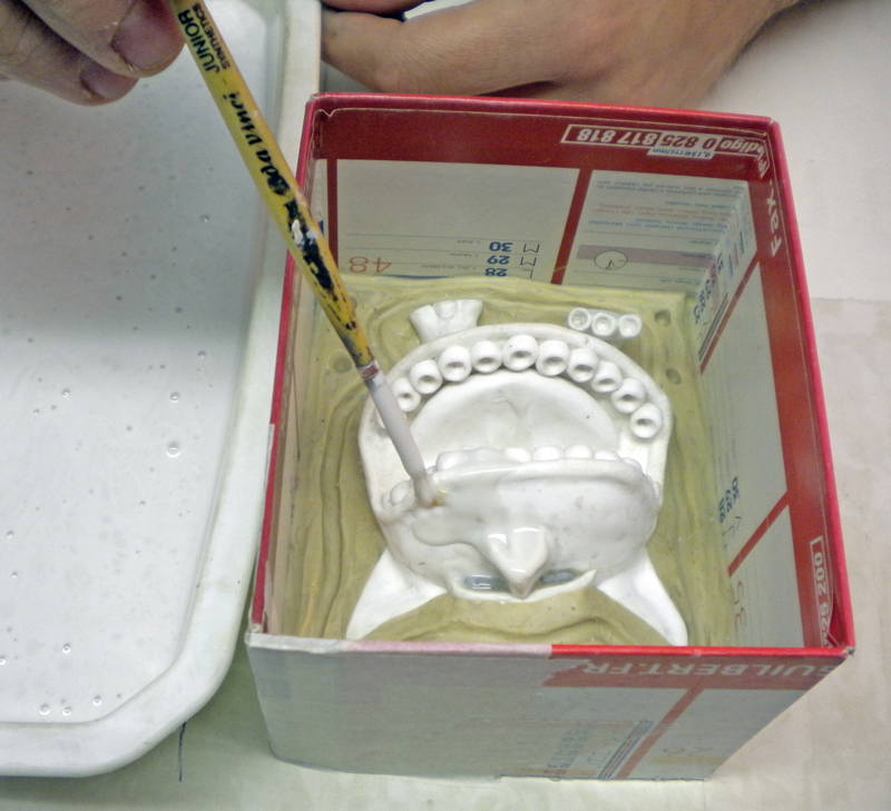 Application au pinceau de silicone sur un modèle en plâtre dans un coffrage en carton