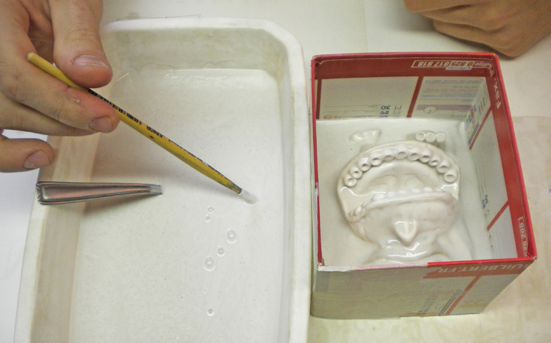 Application au pinceau d'élastomère silicone sur un modèle en plâtre dans un coffrage