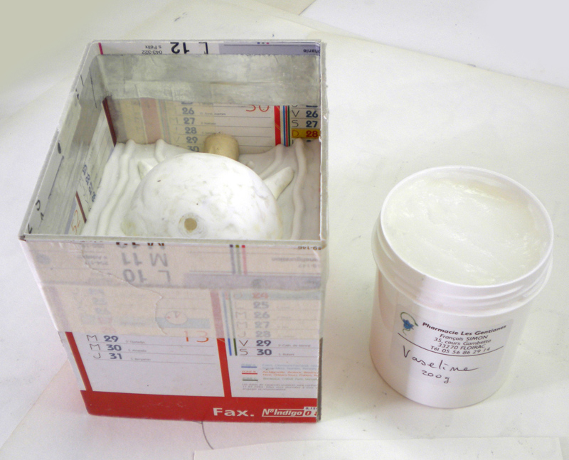 Modèle en plâtre enduit de vaseline dans un coffrage en carton près d'un pot