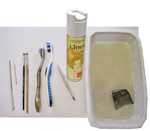 Outils de maquettisme : pinceaux, brosses à dents, laque Elnett et bac avec pièce métallique trempée