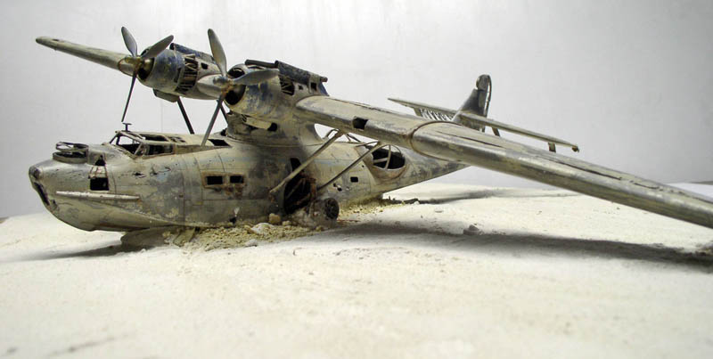 Maquette d'hydravion PBY Catalina vieillie posée sur un diorama de plage sablonneuse