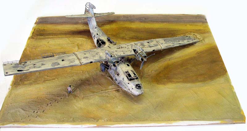 Maquette d'hydravion PBY Catalina vieilli posée sur un diorama désertique avec figurine
