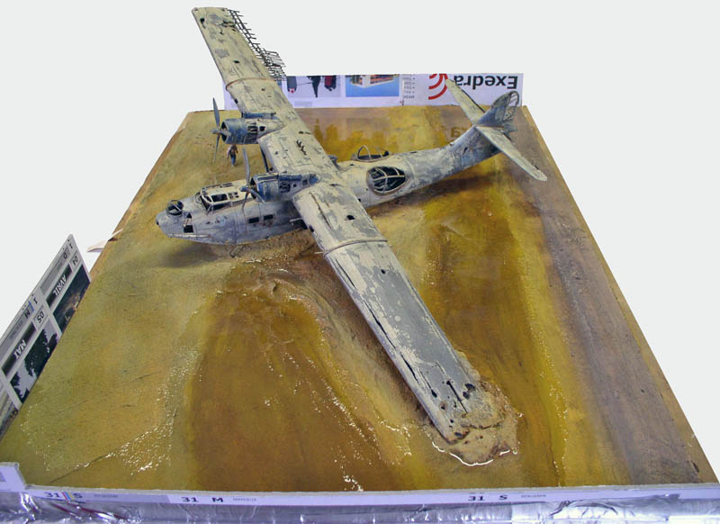 Maquette d'hydravion PBY Catalina vieilli posé sur un diorama de plage sablonneuse