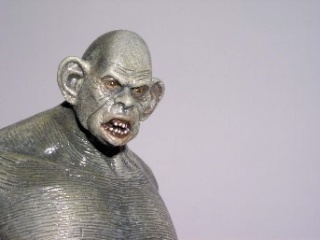 Buste de figurine de créature monstrueuse grimaçante photographié sur fond gris uni neutre