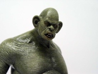 Figurine d'ogre vert peinte photographiée en gros plan sur fond blanc neutre