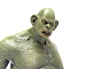 Gros plan d'une figurine de créature monstrueuse grisâtre photographiée sur fond noir