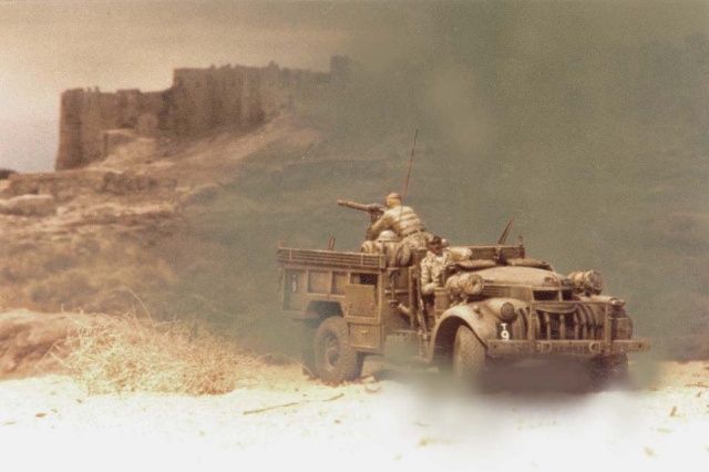 Maquette de camion militaire avec soldats dans un désert devant une forteresse fortifiée