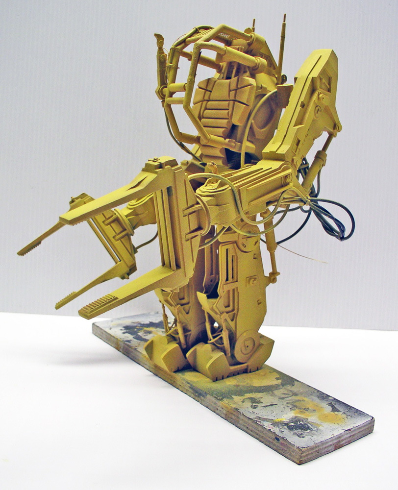 Maquette du Powerloader Aliens en apprêt jaune, montée sur socle de peinture