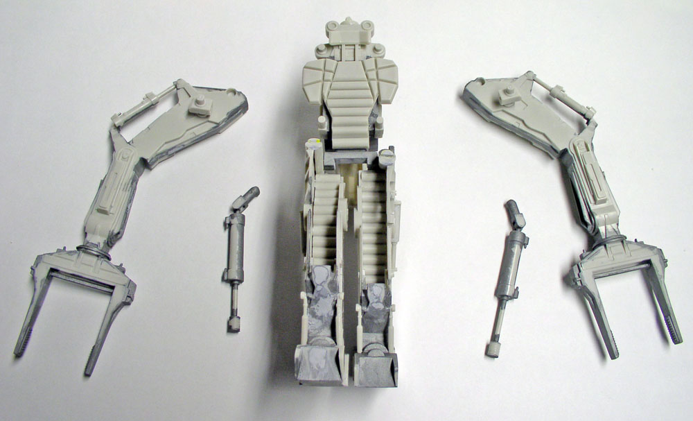 Sous-ensembles gris assemblés du Powerloader : bras à pinces, vérins et structure centrale posés sur fond clair