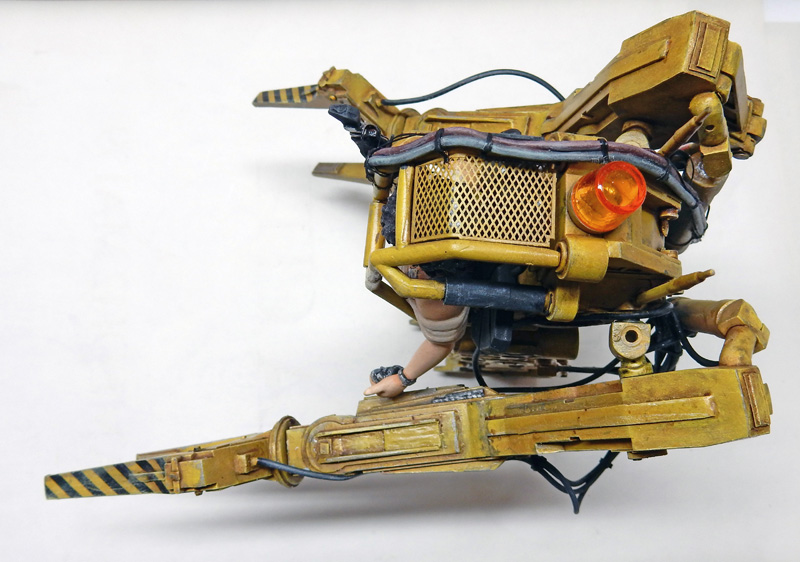 Maquette du Powerloader jaune d'Aliens, vue de profil avec figurine de pilote et gyrophare orange
