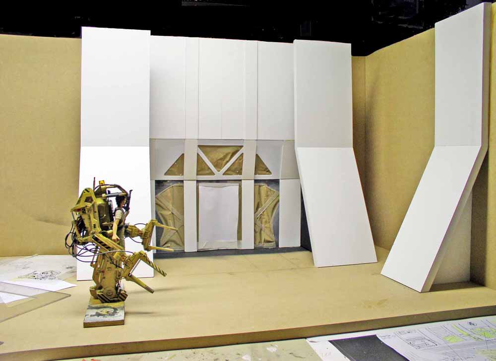 Maquette du Powerloader Aliens devant un décor de hangar en construction avec panneaux blancs