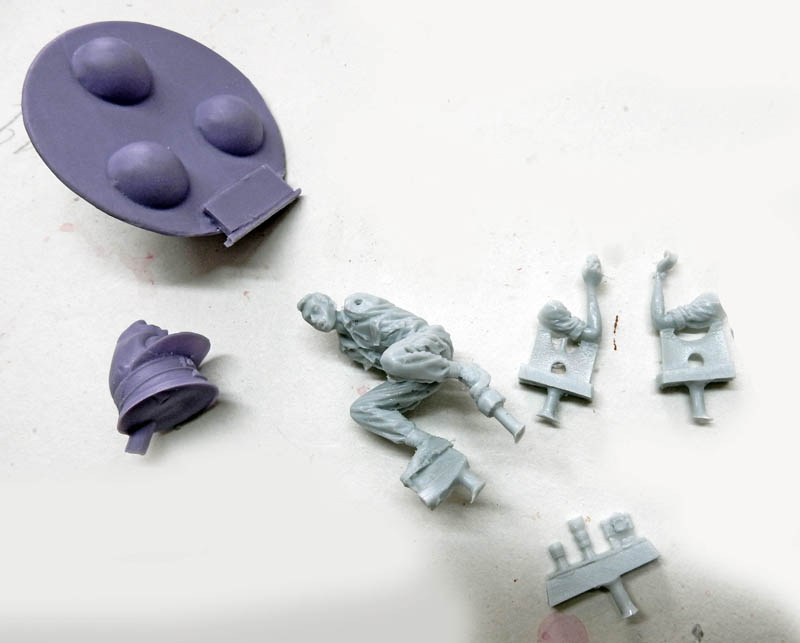 Pièces de figurine en résine grise avec moule violet sur plan de travail