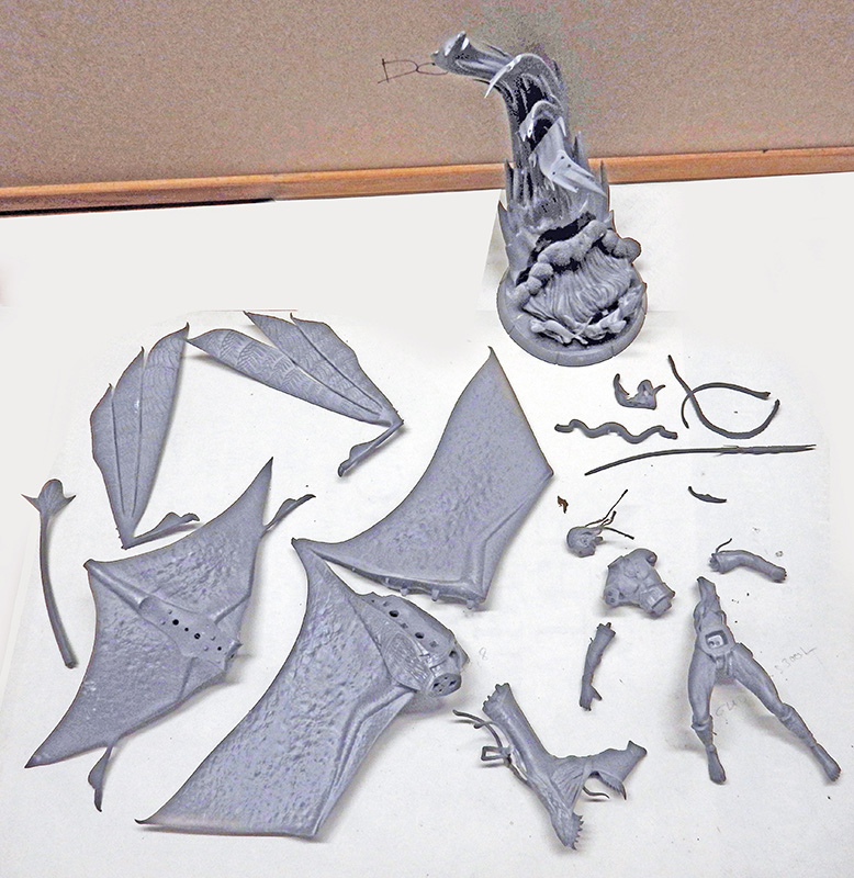 Pièces de figurine de dragon imprimées en résine grise disposées avant assemblage et nettoyage