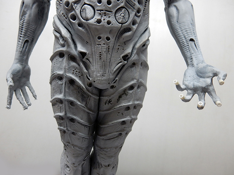 Torse et jambes gris de la maquette Prometheus en cours d'assemblage, main aux doigts percés visible