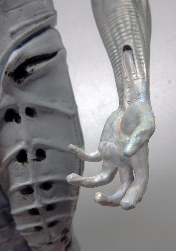 Gros plan sur la main et le bras nacrés d'une figurine Prometheus en cours de peinture