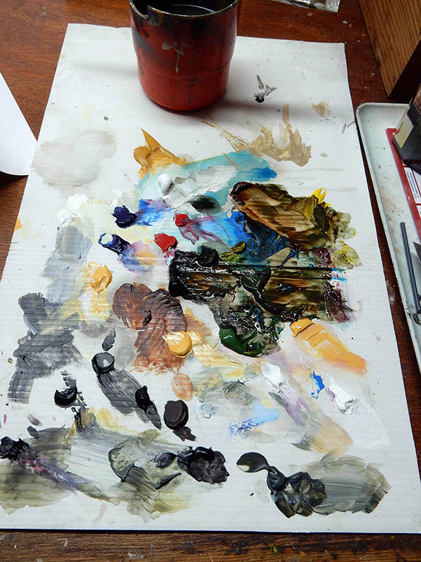 Palette de peinture improvisée sur papier avec mélanges de couleurs et pot rouge pour le maquettisme