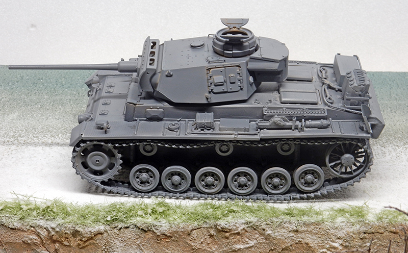 Maquette de char Panzer III gris vue de profil sur un diorama herbeux