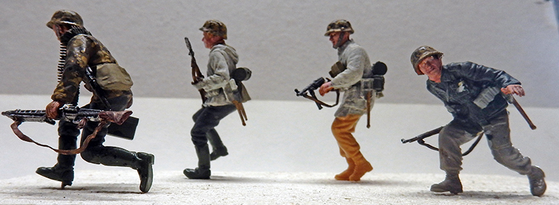 Quatre figurines de soldats allemands à l'assaut, armés, accompagnant la maquette du Panzer III