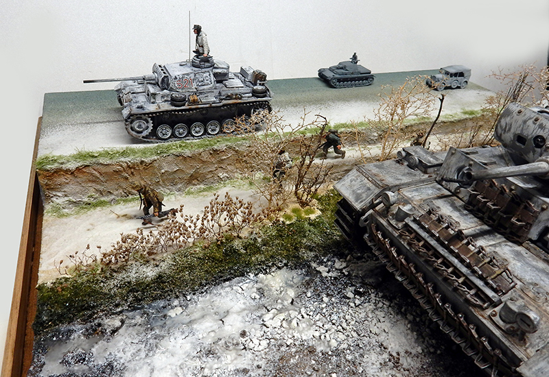 Diorama hivernal avec maquette de Panzer III gris, char détruit et figurines de soldats progressant dans un paysage enneigé