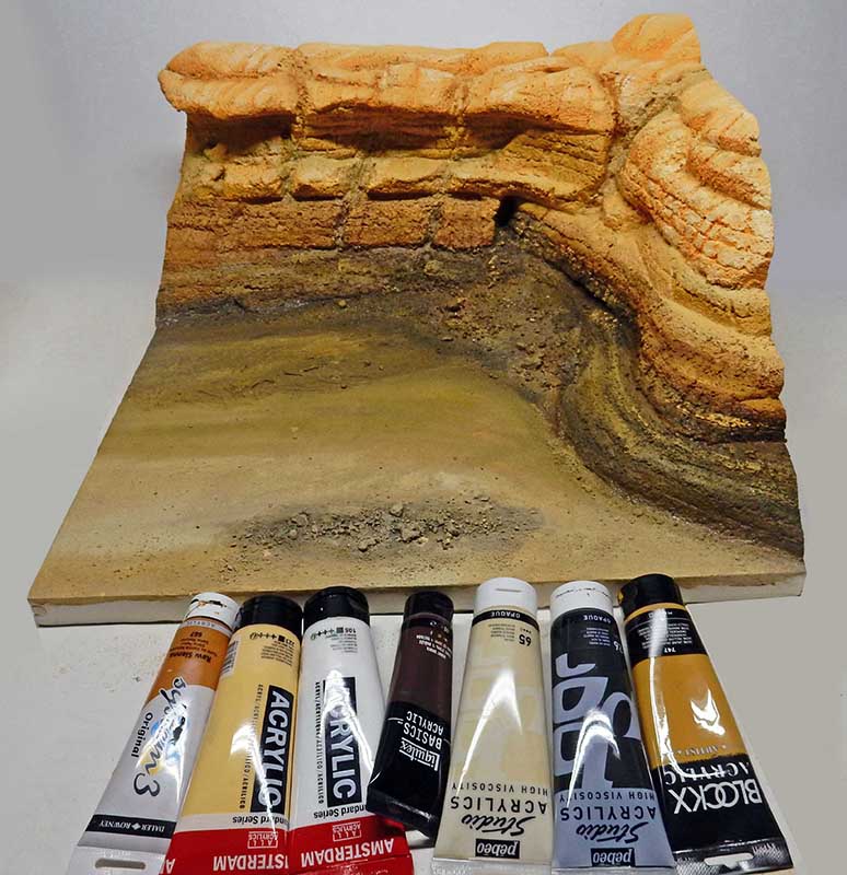 Diorama de décor désertique en cours de peinture avec tubes de peinture acrylique au premier plan