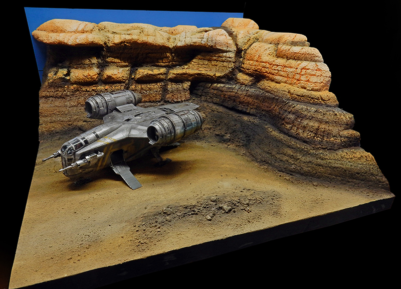 Maquette du Razor Crest posée sur un diorama désertique avec falaises rocheuses stratifiées