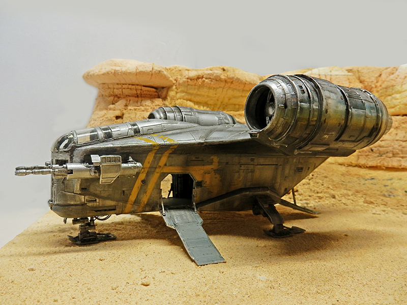 Maquette du Razor Crest posée sur un diorama désertique, rampe d'accès abaissée