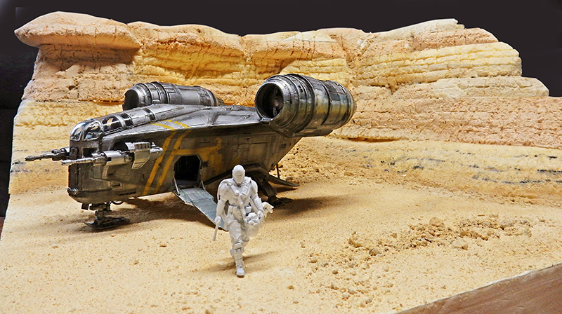 Maquette du Razor Crest posée dans un diorama désertique avec figurine du Mandalorien descendant la rampe