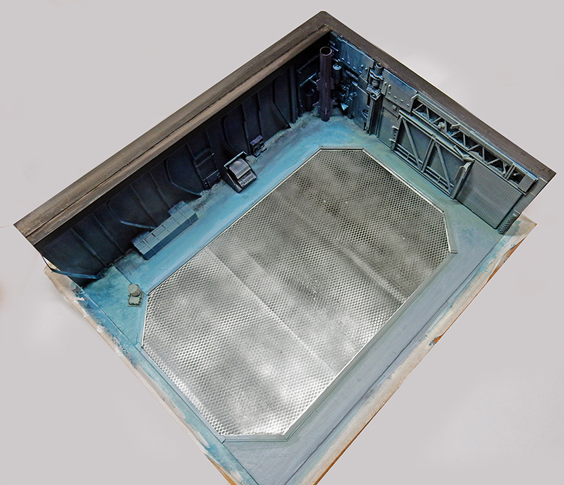 Maquette de décor industriel avec sol en tôle gaufrée et parois métalliques sombres