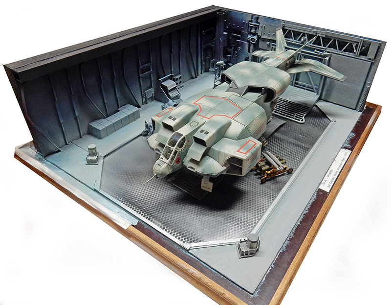 Maquette de vaisseau spatial gris dans un diorama de hangar militaire de science-fiction