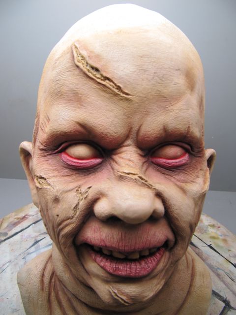 Buste de figurine peint représentant un visage démoniaque aux yeux blancs et cicatrices