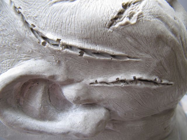 Gros plan sur le visage sculpté de Regan avec plaies et oreille modelées avant peinture